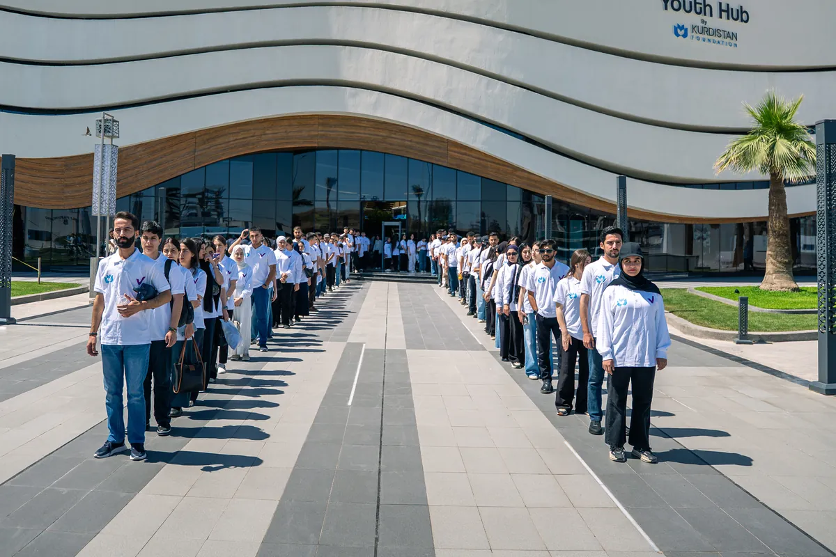 Young volunteers in Kurdistan Foundation shirts line the approach to the Youth Hub
